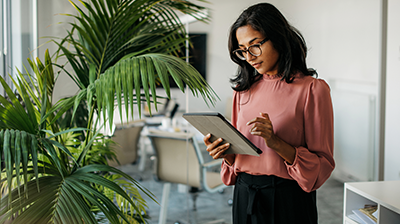 Digital and Traditional: Find the Best of Both Worlds A woman standing next to a tall plant while using her tablet