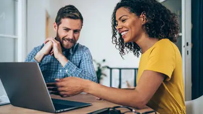 The Latest Ivans Product Updates All in One Place A man and a woman sitting at table while the woman is showing him something on a laptop