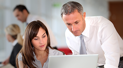 Direct Bill Commission Statement Download Man and woman in business attire looking at laptop together